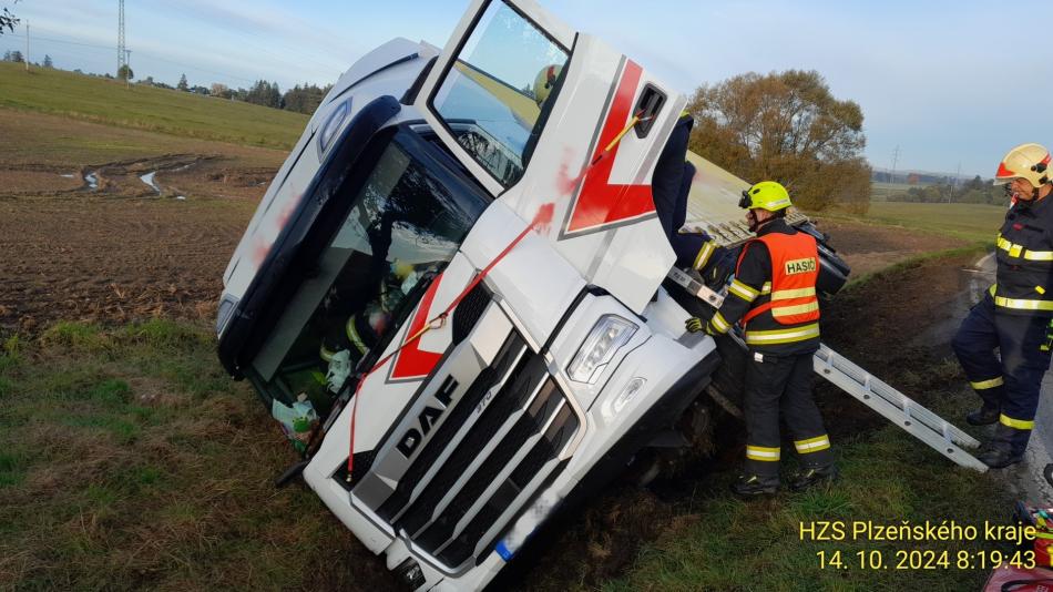 Řidič neovládl v zatáčce kamion, skončil v příkopě. Vyprošťovat ho museli hasiči